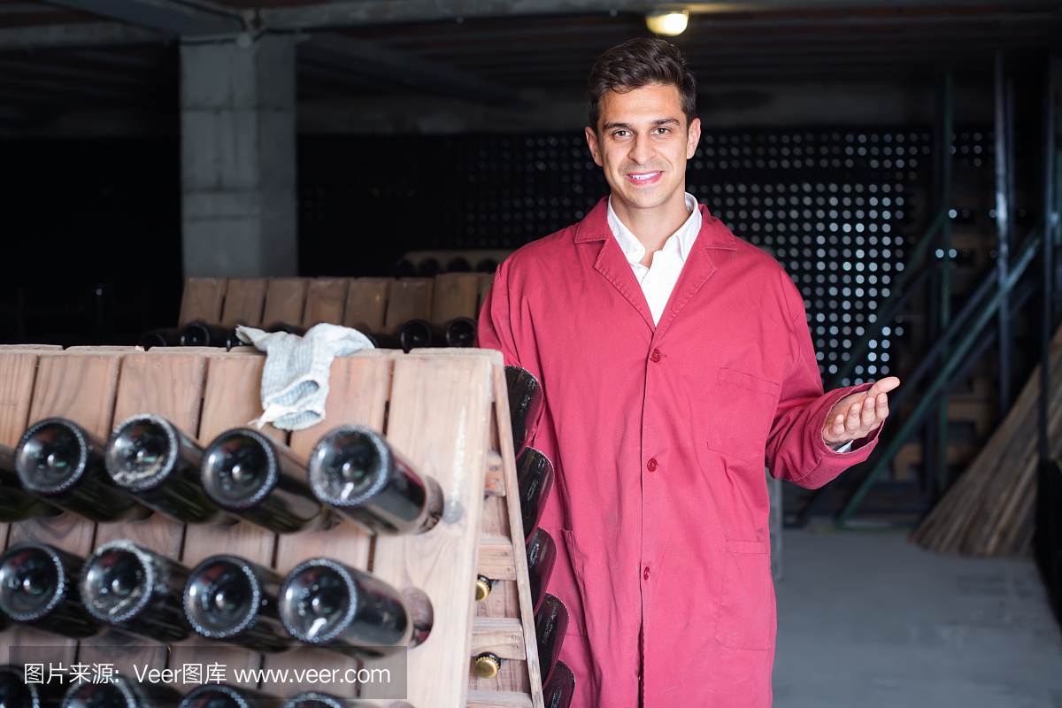 微笑的男人穿着制服工作与瓶子储存架